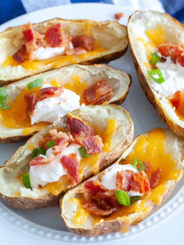 Plate of air fryer potato skins loaded with sour cream, cheese and bacon. 