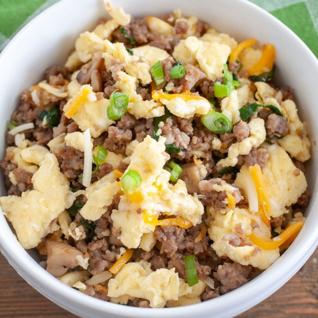 white bowl with eggs, sausage mushrooms and spinach