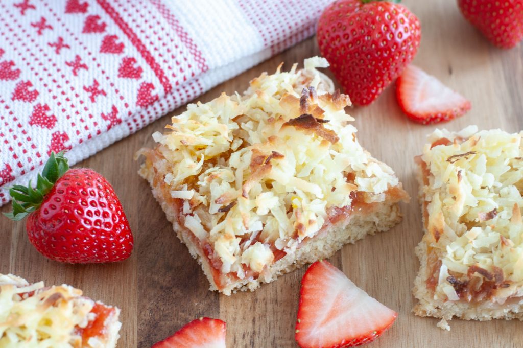 A strawberry coconut bar with cut strawberries and a tea towel with hearts