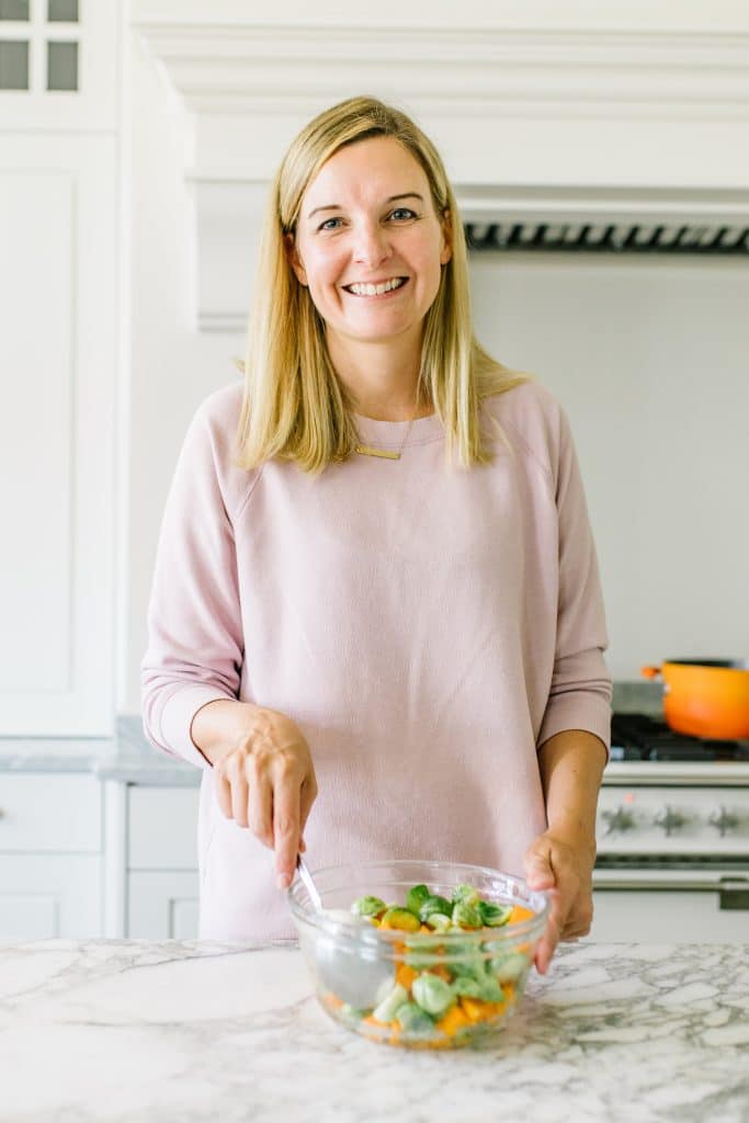 A woman standing in kitchen with a bowl. 