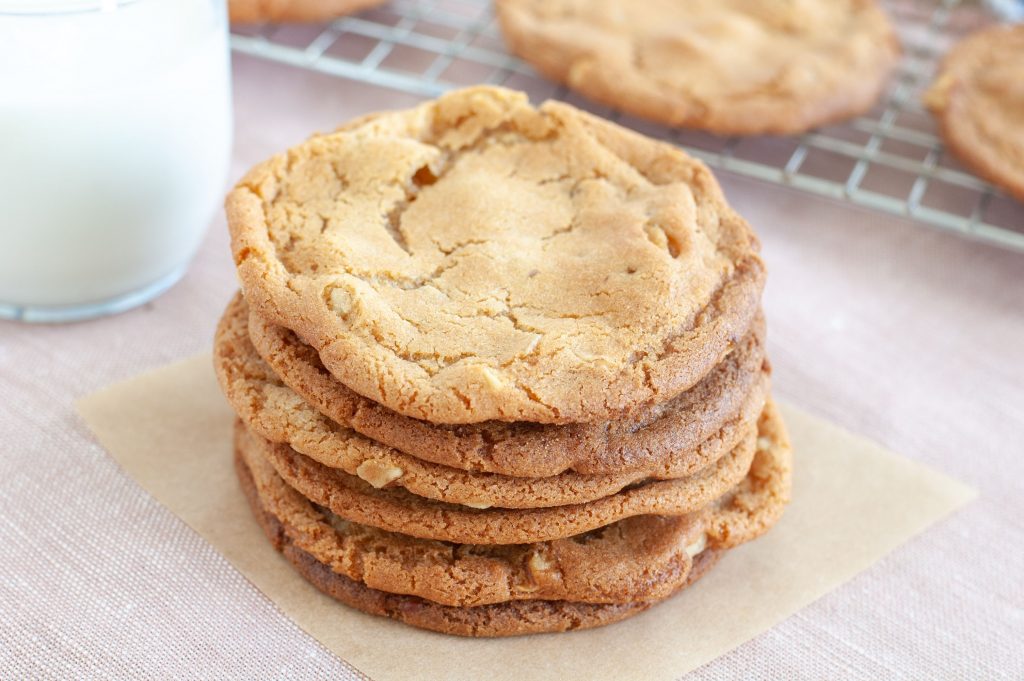 Stack of butterscotch cookies with a glass of milk in background