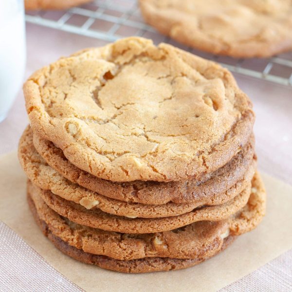 Stack of butterscotch cookies with a glass of milk in background