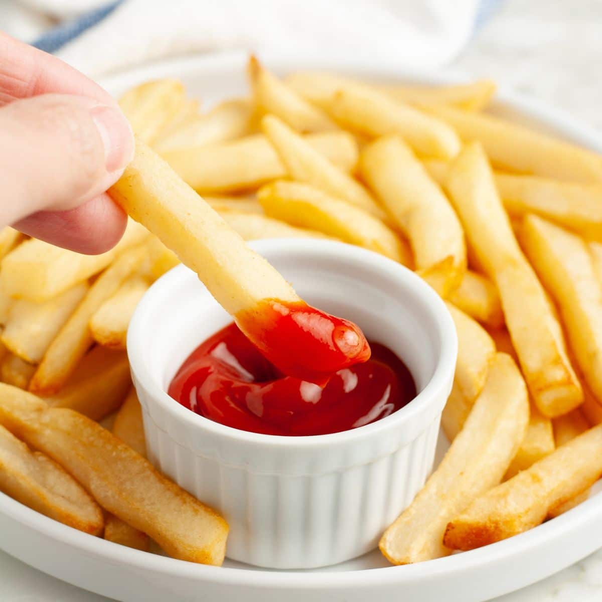 Plate with french fries and bowl of ketchup.