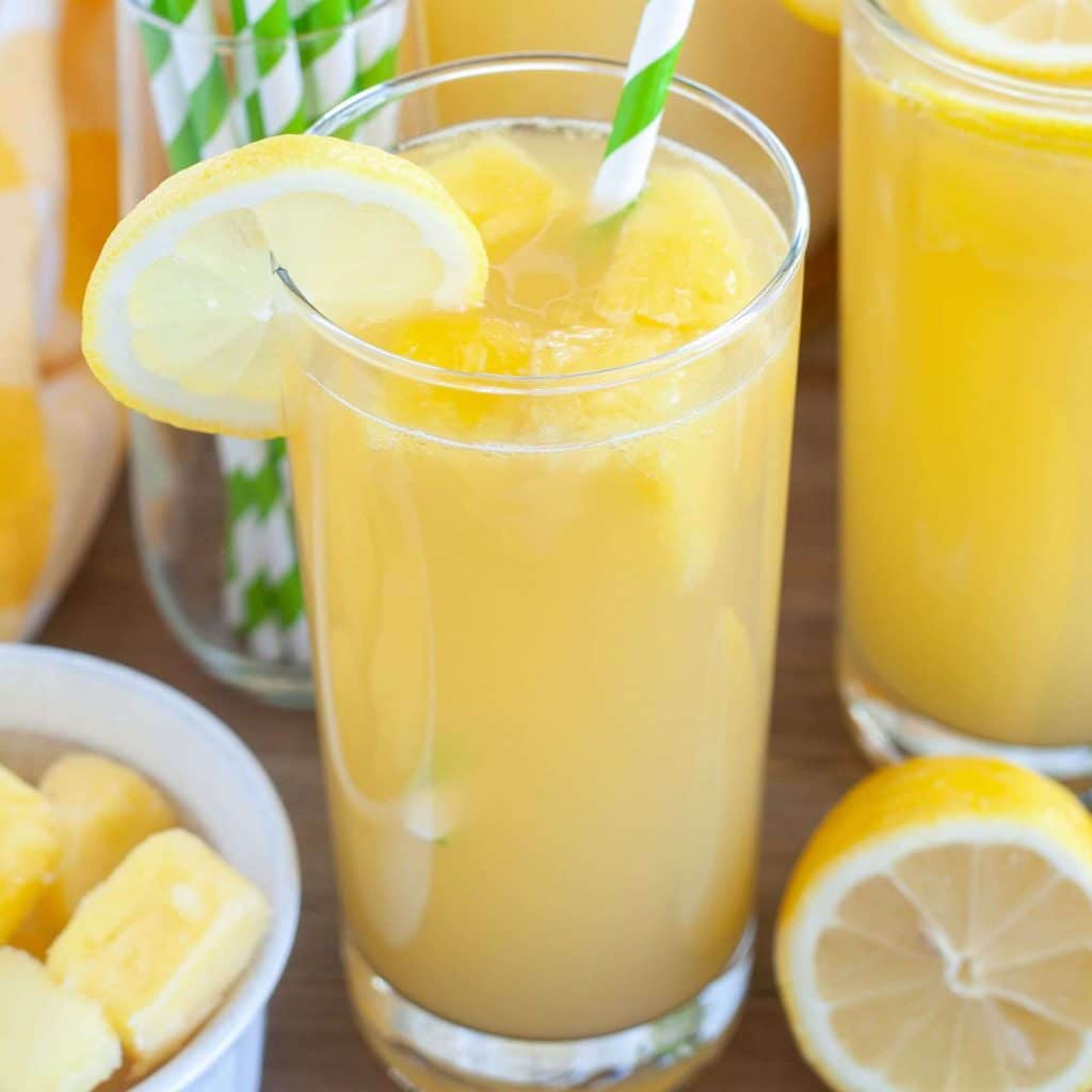 Pineapple lemonade in a glass with green striped straw