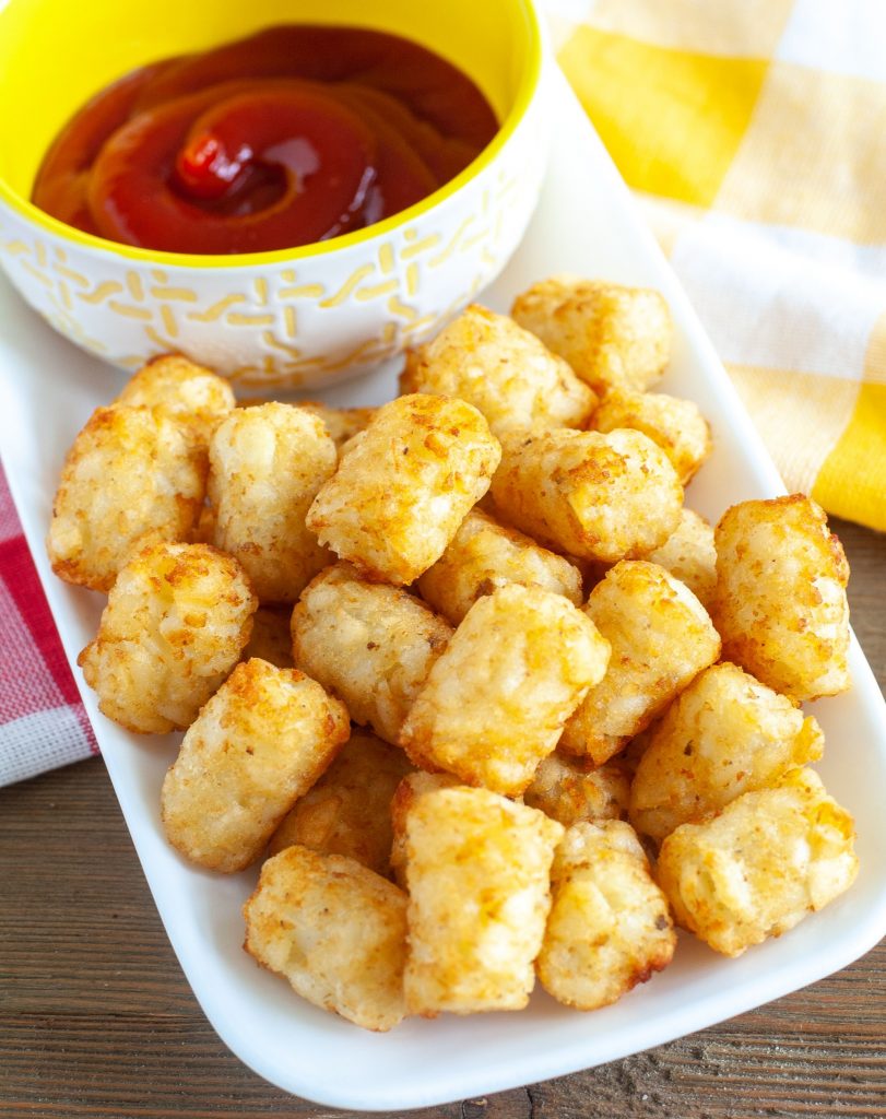 Tator tots on a plate with bowl of ketchup