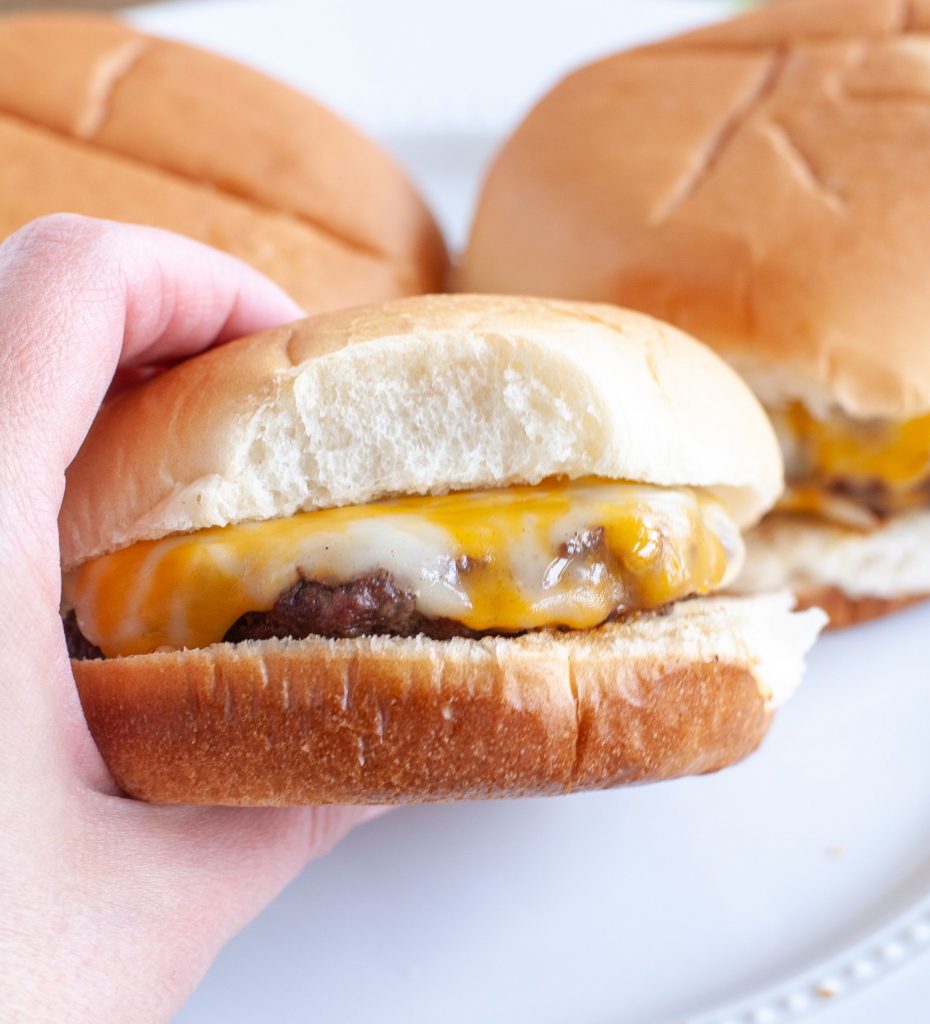 Hand holding cheeseburger