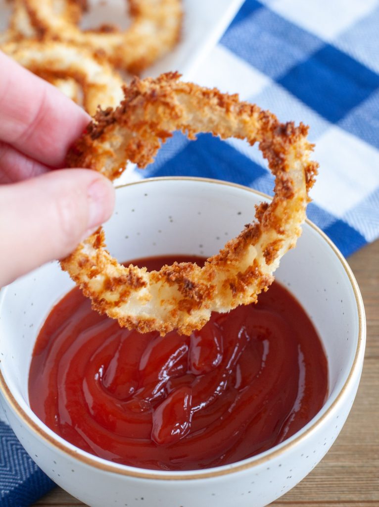 Onion ring being dipped in ketchup