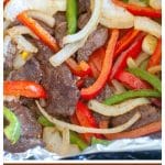 Steak, peppers and onions on foil.