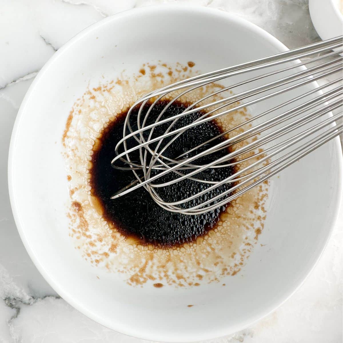 Bowl of soy sauce with a whisk. 