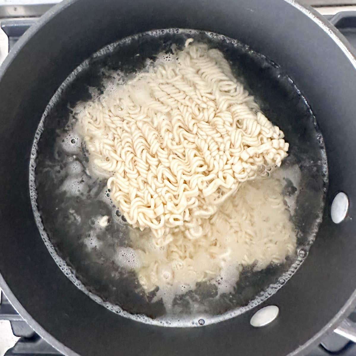 Pot with water and ramen noodles. 