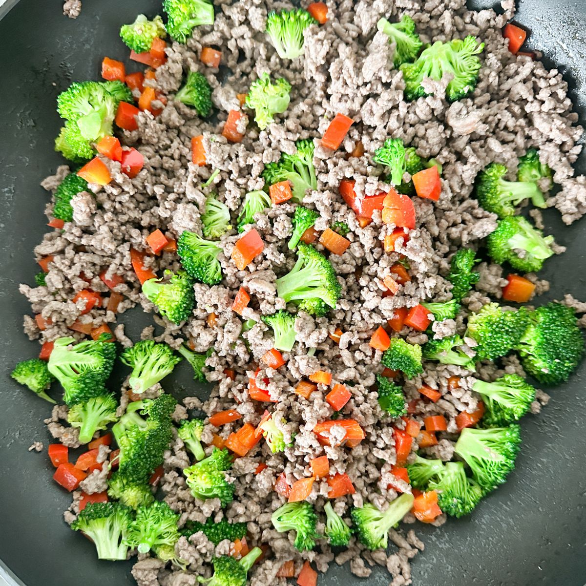 Skillet with ground beef, broccoli, and red peppers. 