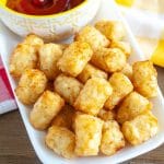 Tator Tots on a plate with bowl of ketchup.
