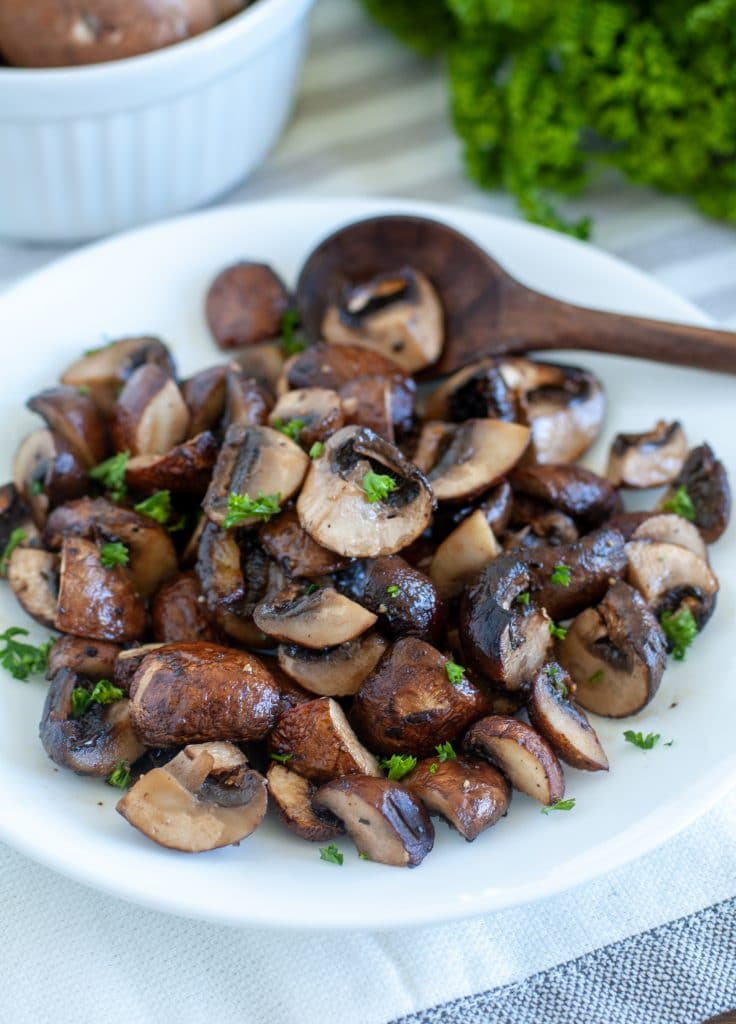 Plate with air fryer roasted mushrooms and small wooden spoon