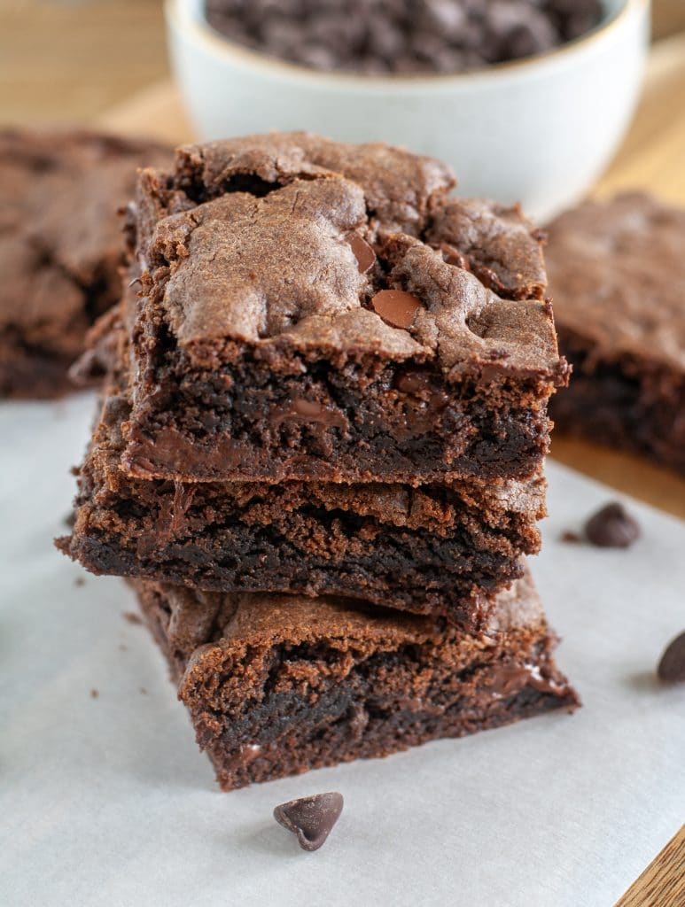 Stack of three brownies and chocolate chips. 