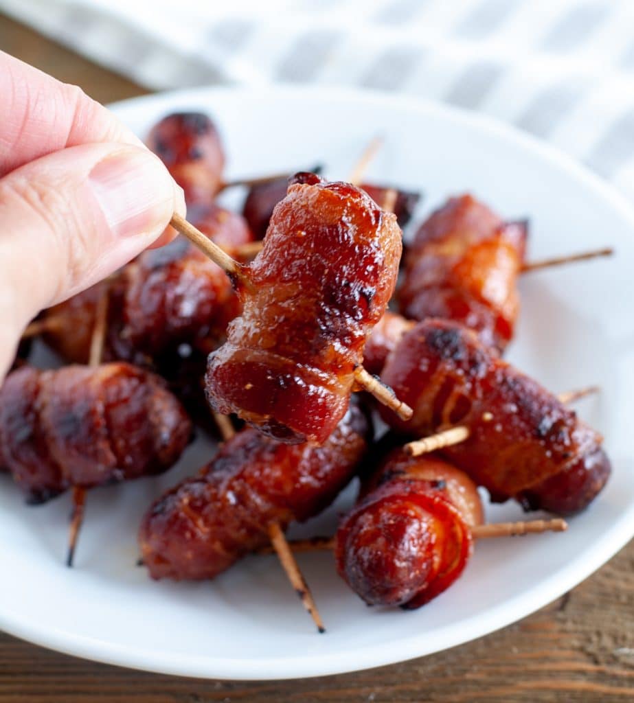 hand holding bacon wrapped smokie