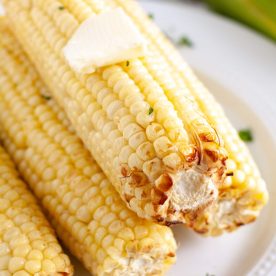 Corn stacked on a plate with pat of butter