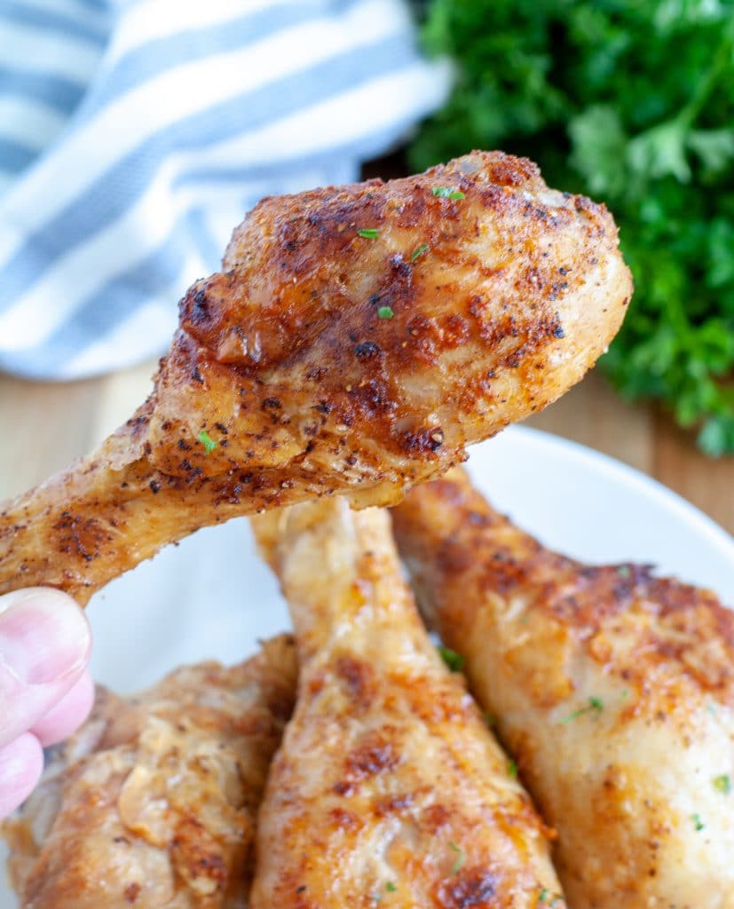 Chicken drumstick being held above a plate