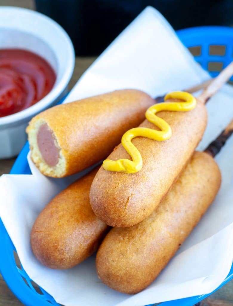 Corn dogs in basket with bowl of ketchup