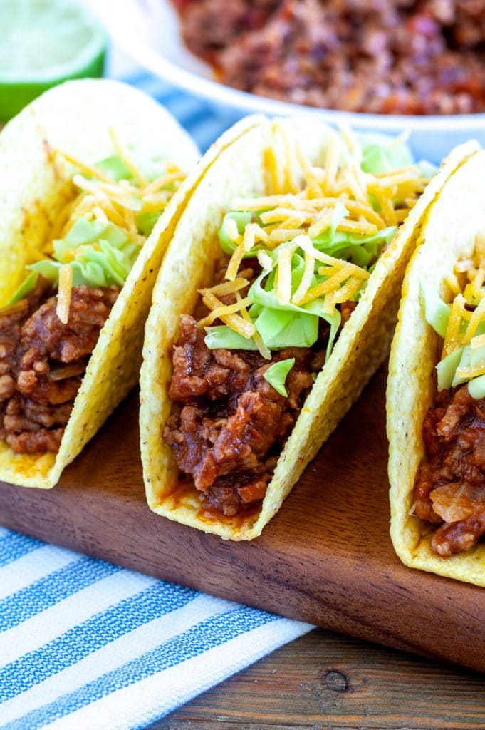 Three taco shells with ground beef cheese and lettuce