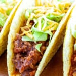 Ground beef tacos on a wooden board.