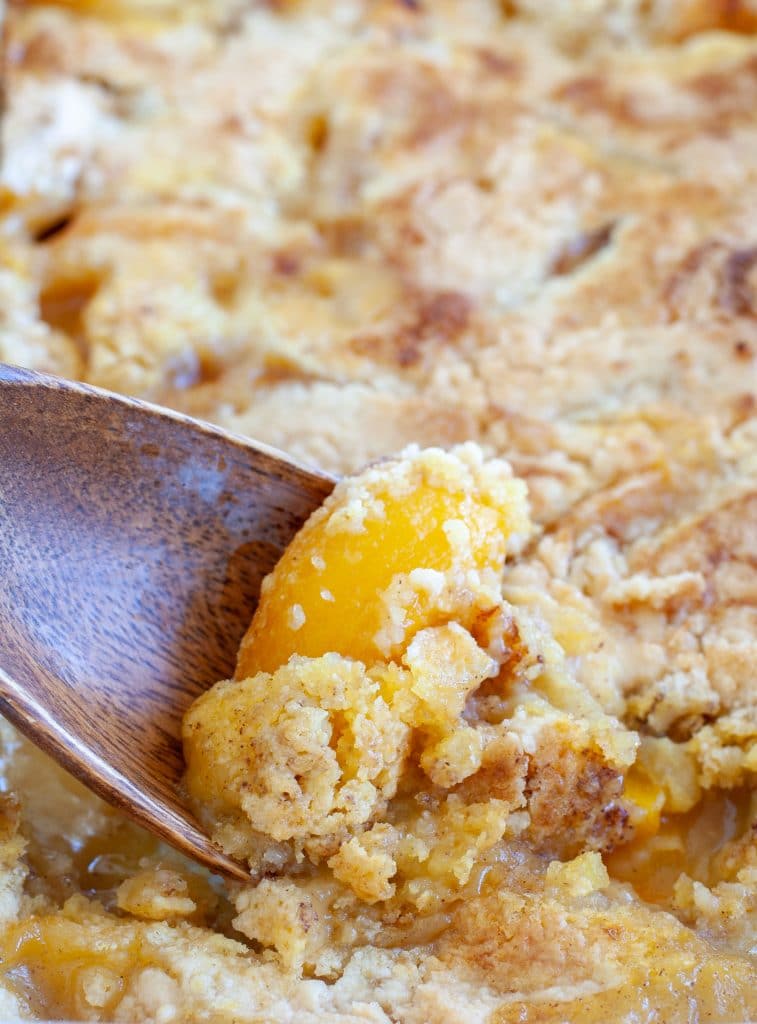 Wooden spoon in peach cobbler