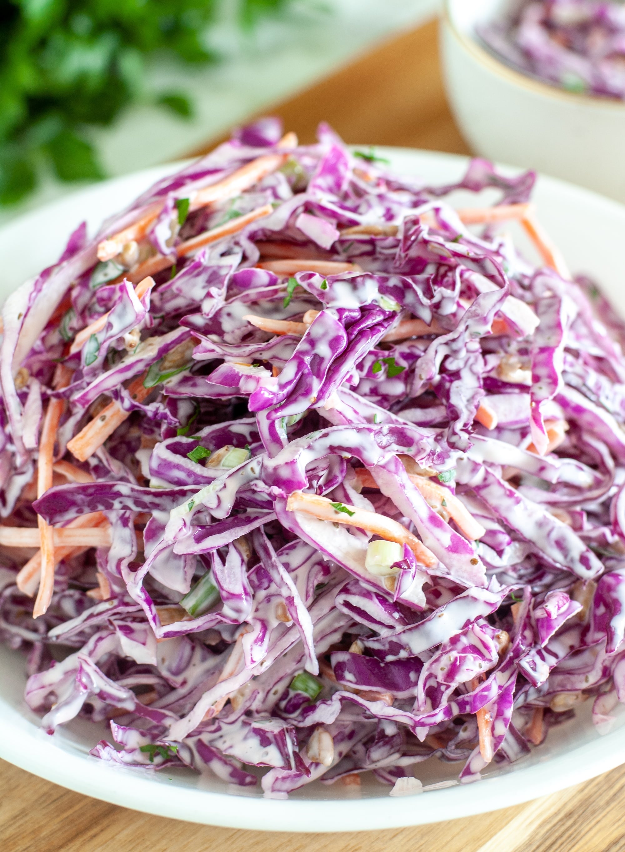 Piled high red cabbage coleslaw on a white plate, showcasing its vibrant purple color and creamy dressing