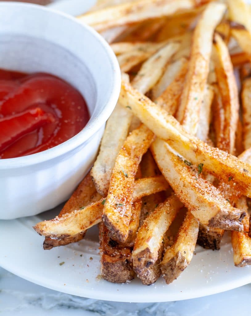 Plate of french fries with bowl of ketchup