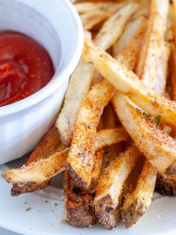 French fries on plate with ketchup.