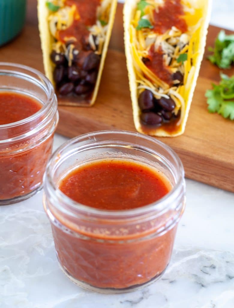 Taco sauce in a jar with tacos in back