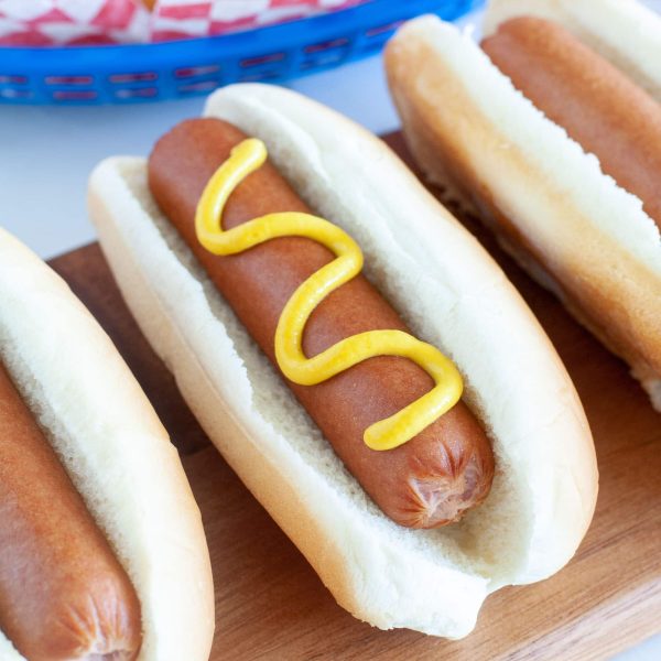 hot dog on a board with mustard