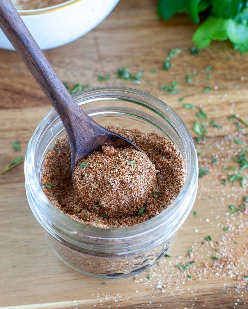 Jerk seasoning in a jar with wooden spoon