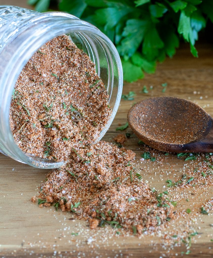 Seasonings spilling out of a jar with wooden spoon