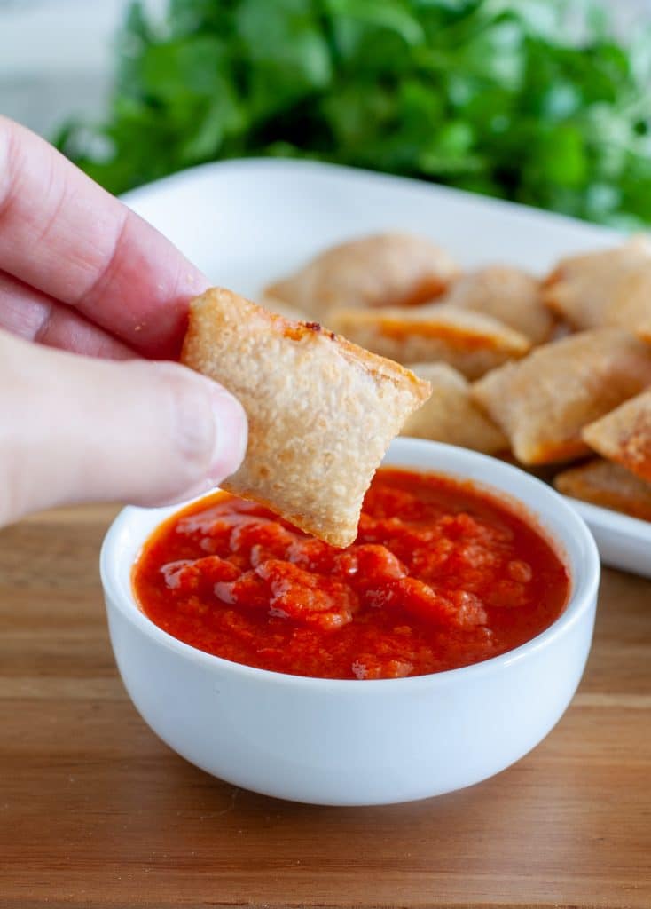 pizza roll being dipped in marinara