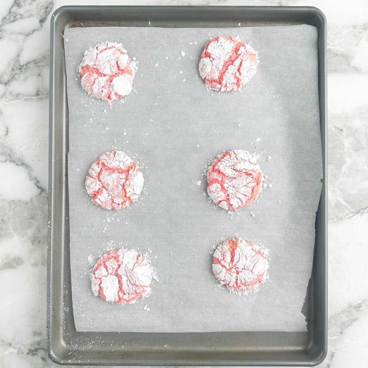 Baking pan with cooked strawberry crinkle cookies.
