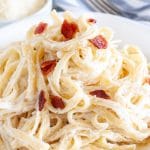 Pasta on a plate with bacon bits on top