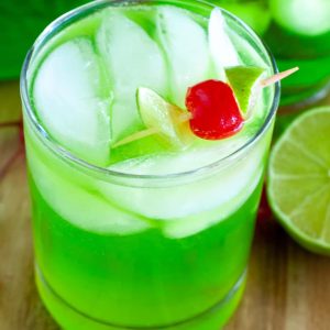 Glass with green drink and a cherry.