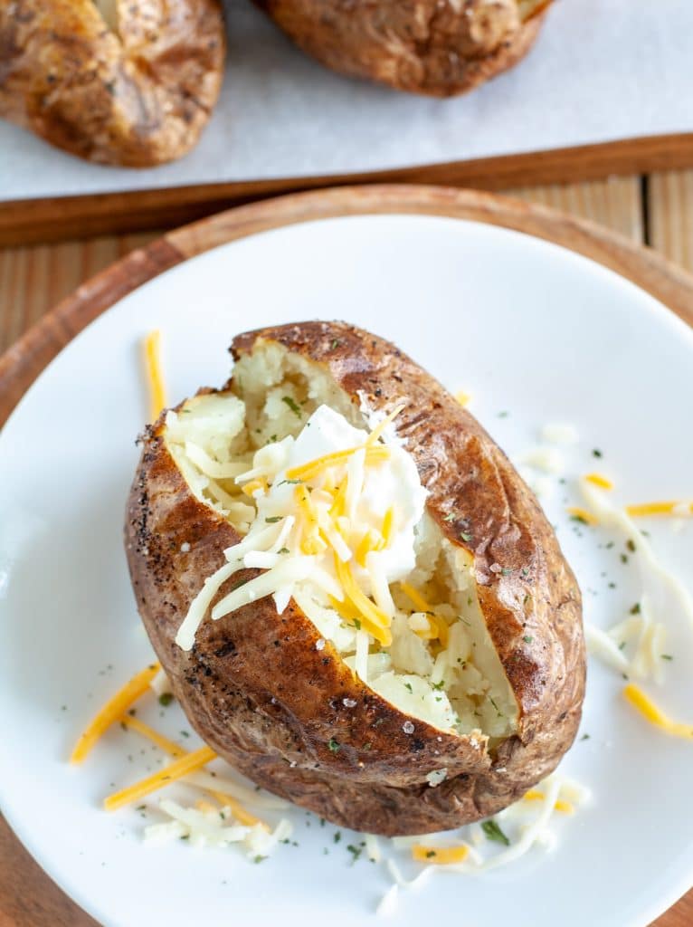 Baked potato on a plate with sour cream and cheese