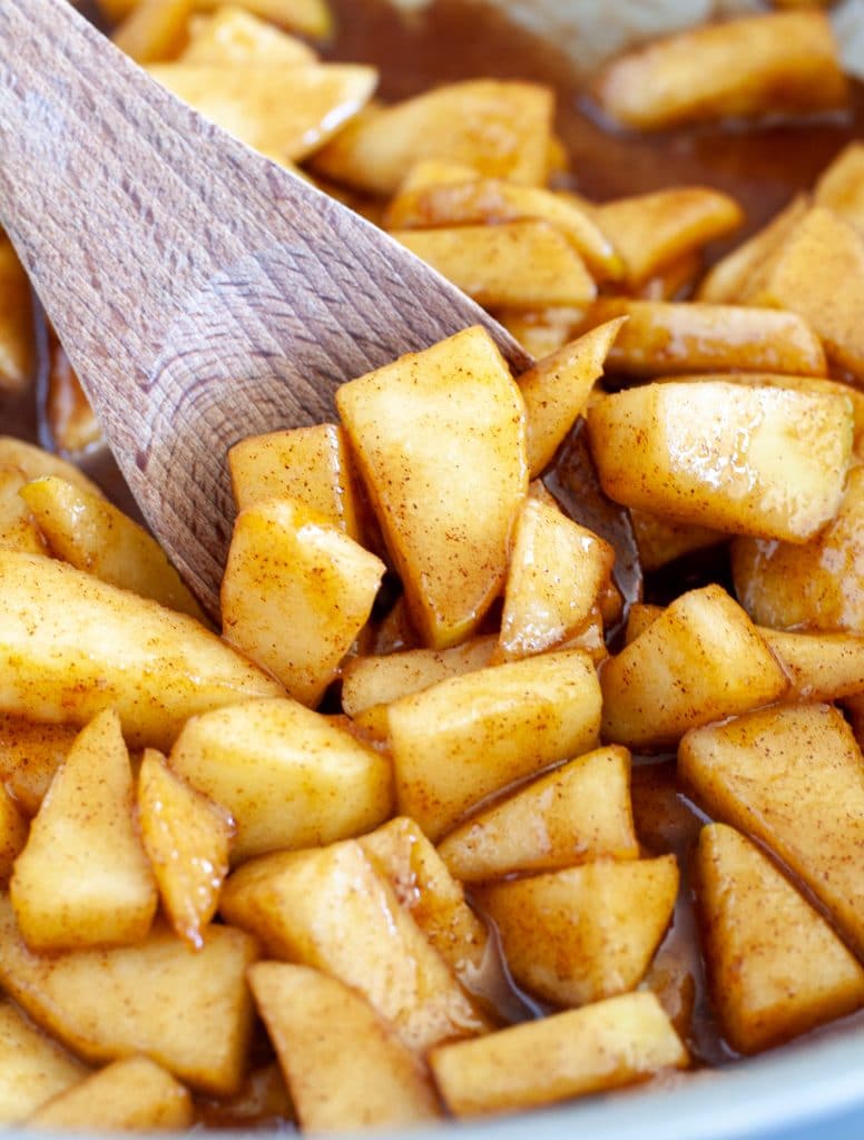 Skillet of cinnamon apples with wooden spoon