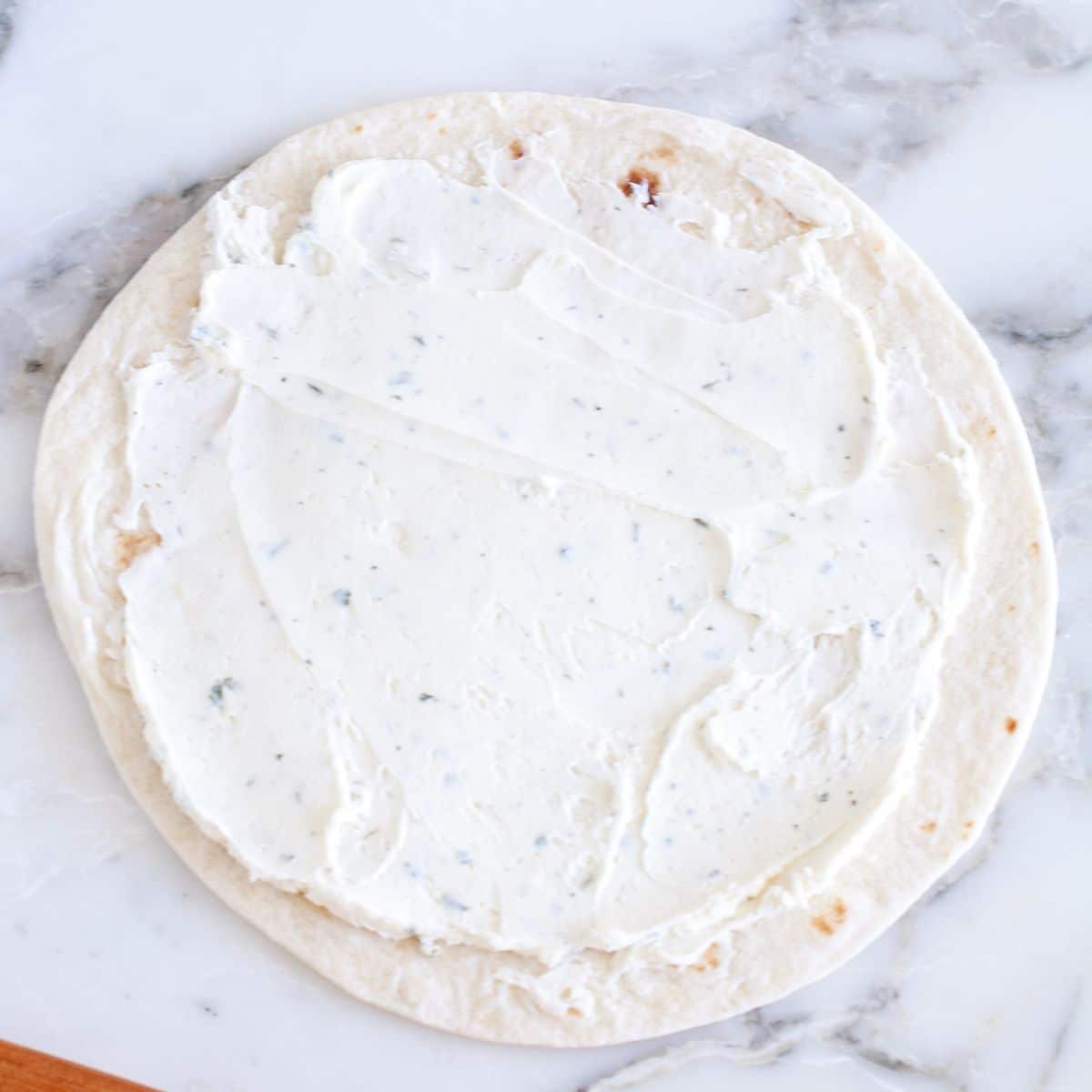 Tortilla with cream cheese spread on top.