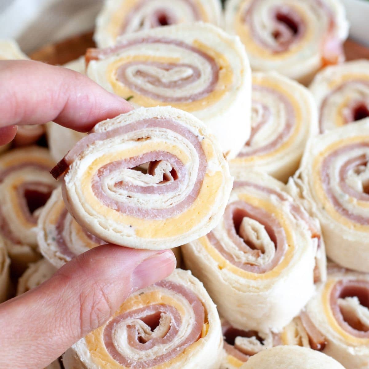 Hand holding a ham and cheese roll-up.