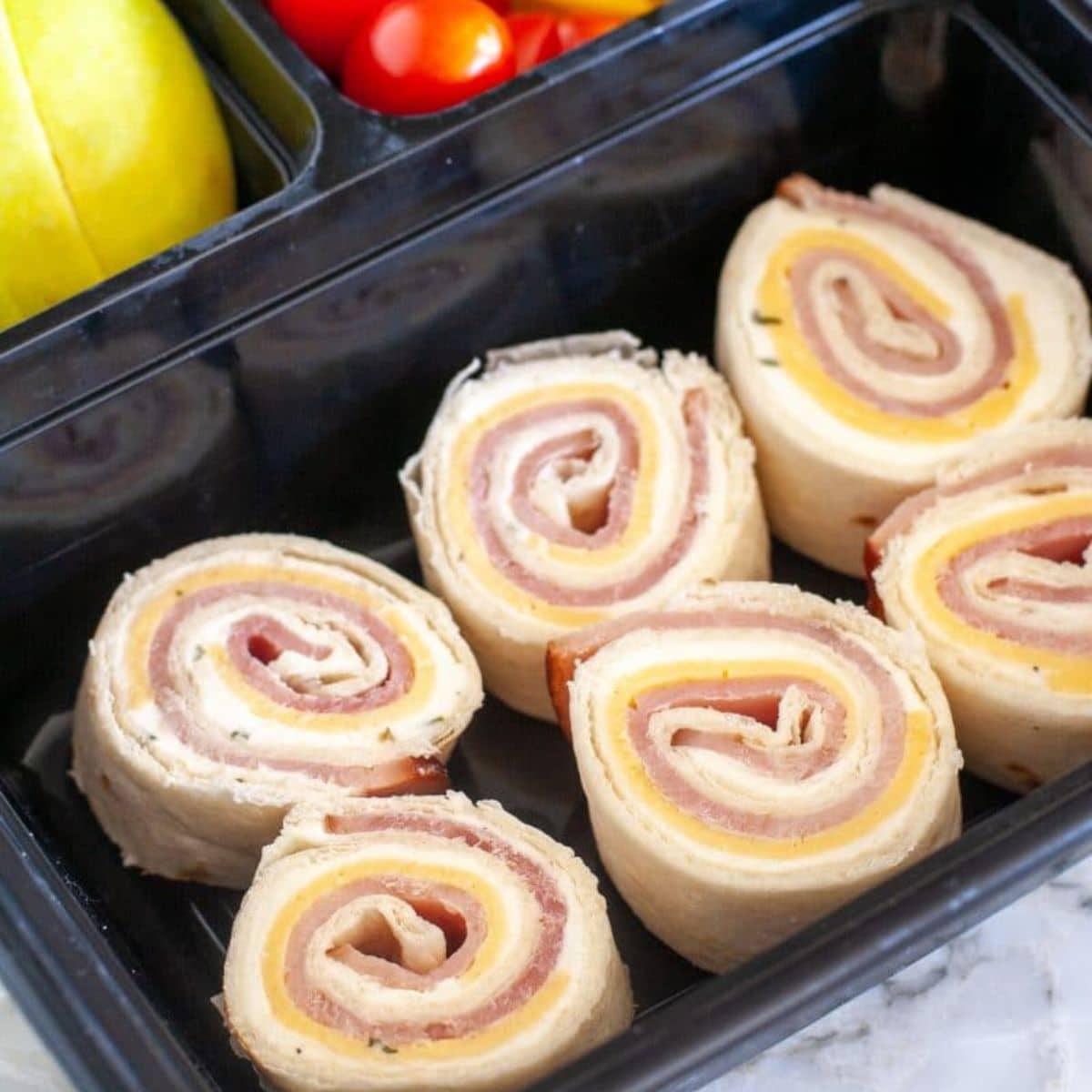 Ham and cheese roll ups in a container.