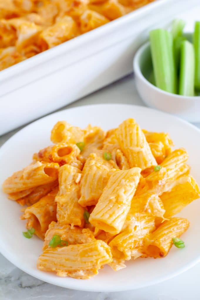 Buffalo chicken pasta bake on a plate with celery in a bowl