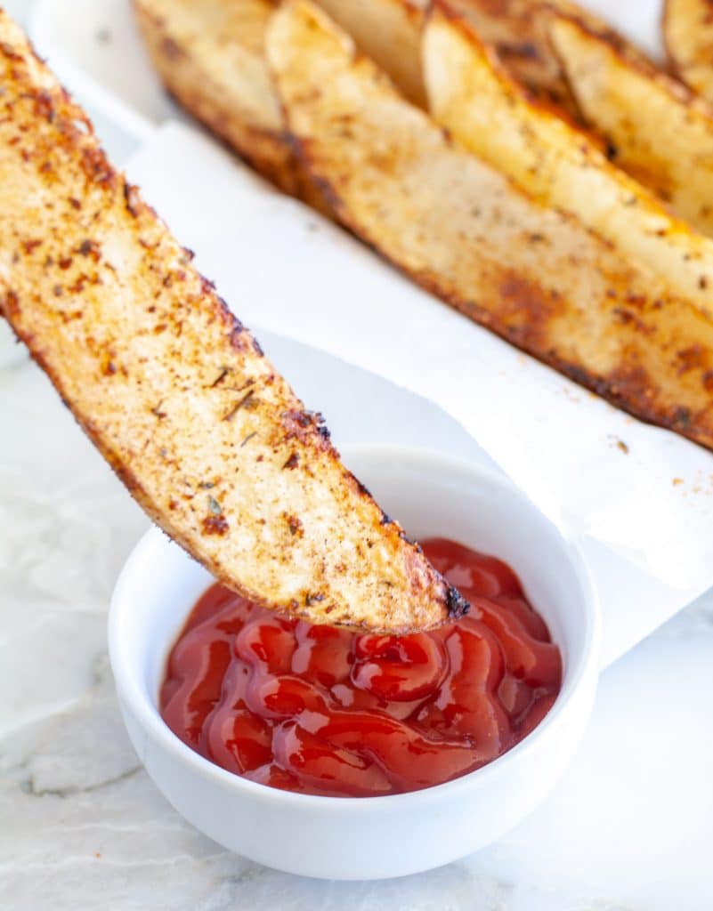 Potato wedge dipped in ketchup