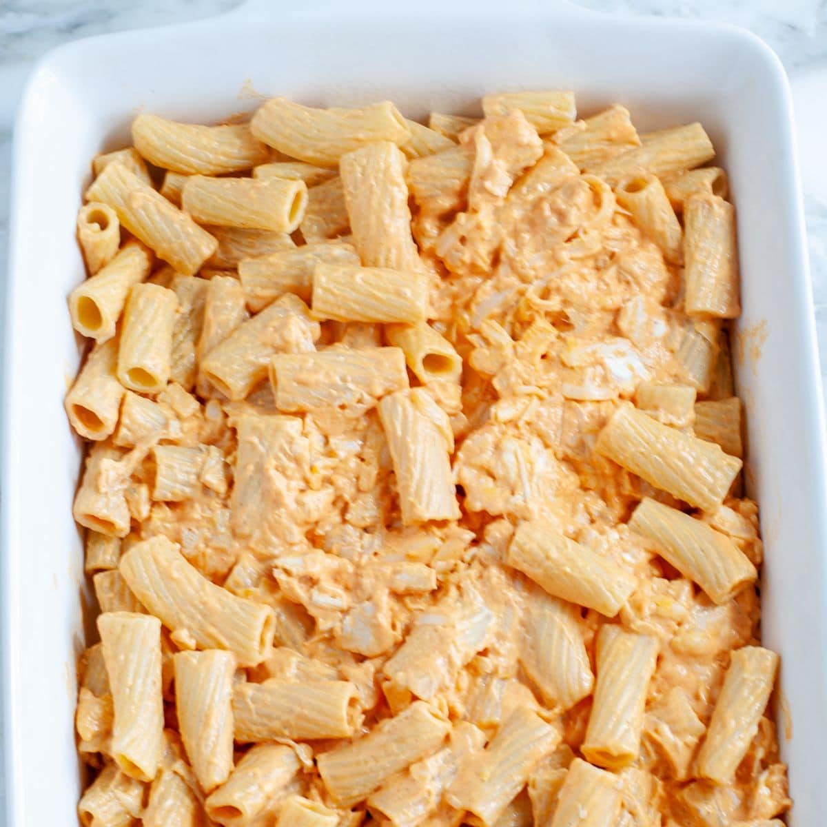 Baking dish with uncooked buffalo pasta bake.