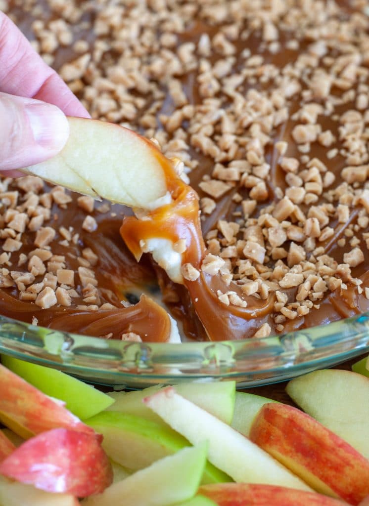 Sliced apple dipping into caramel dip