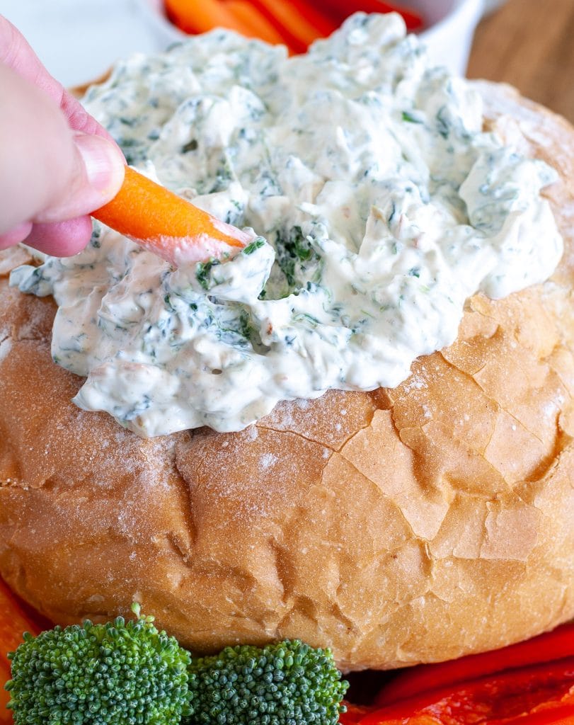 Spinach dip with carrot being dipped