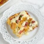 Plate with a piece of eggs Benedict casserole topped with Hollandaise sauce.