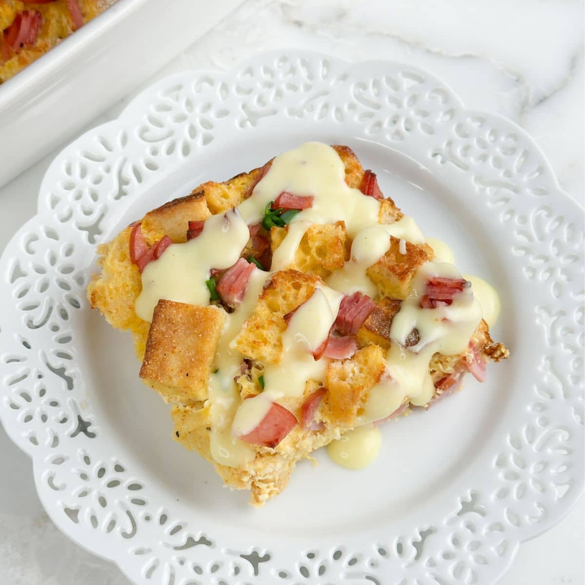 Plate with a piece of eggs Benedict casserole topped with Hollandaise sauce.