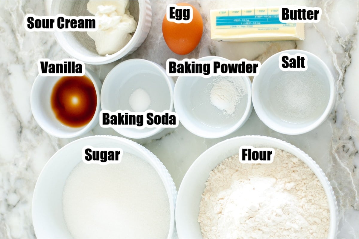 Sour cream, vanilla, egg, butter, bowls of sugar, flour, baking powder, and baking soda.