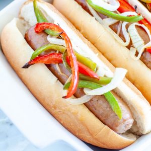 Brat in a bun with onions and peppers.